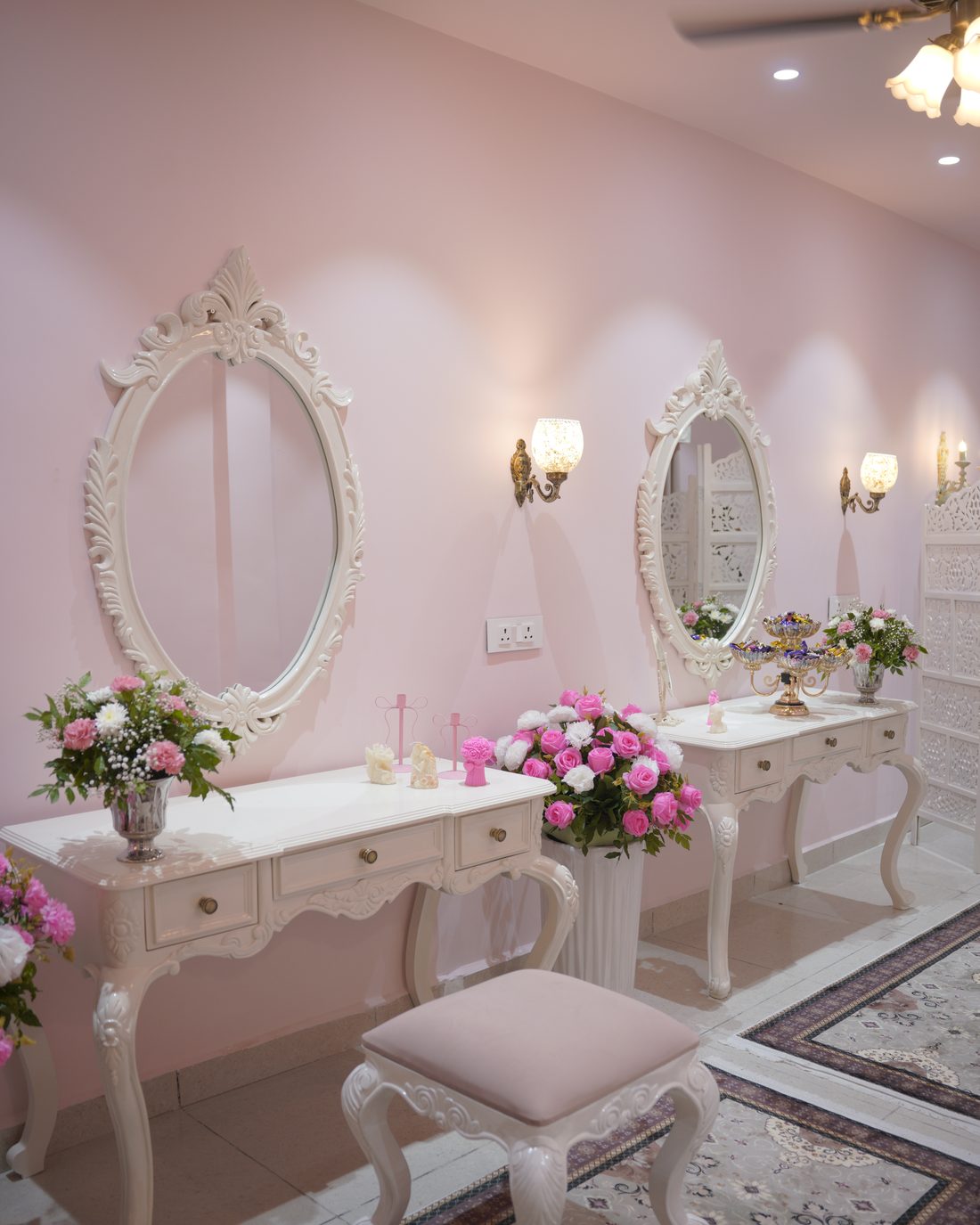 Twin vanity stations with ornate white mirrors and fresh flowers
